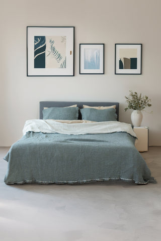 Green muslin bedspread draped on bed showing handwoven 4-layer weave by Vivamaison