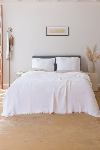 White muslin bedspread draped on bed showing handwoven 4-layer weave by Vivamaison