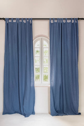 Two blue tab top panels framing arched window. Handwoven 2-layer muslin cotton curtain, Denizli, OEKO-TEX. Vivamaison.