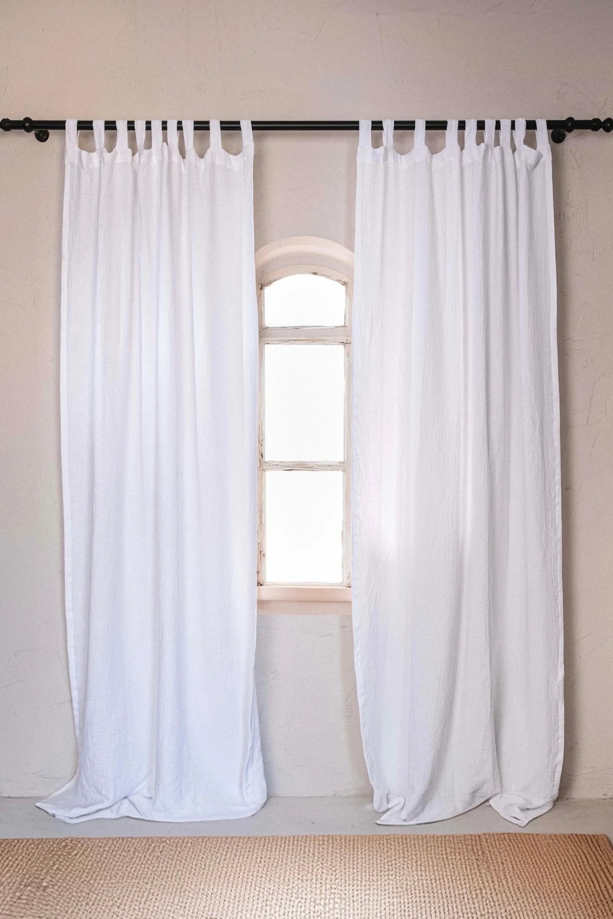 White tab top pair, black rod, arched window. Handwoven 2-layer muslin cotton curtain, Denizli, OEKO-TEX. Vivamaison.