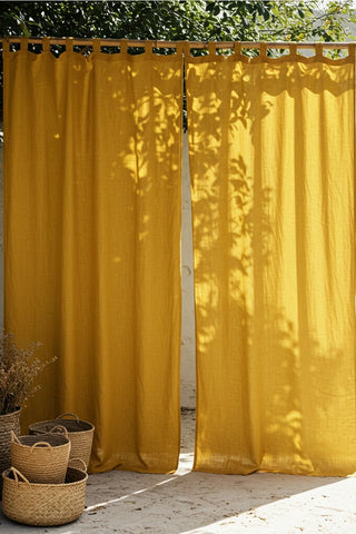 Two mustard tab top panels outdoors on bamboo. Handwoven 2-layer muslin cotton curtain, Denizli, OEKO-TEX. Vivamaison.