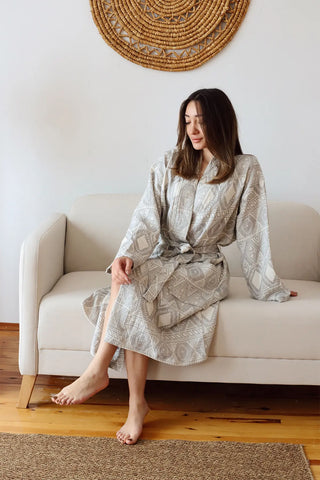 Ethnic anthracite patterned muslin bathrobe seated side lifestyle. Handwoven Turkish cotton Denizli, OEKO-TEX. Vivamaison.