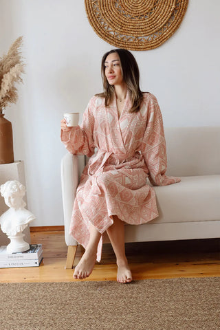 Ethnic pink patterned muslin bathrobe seated with coffee. Handwoven Turkish cotton Denizli, OEKO-TEX. Vivamaison.