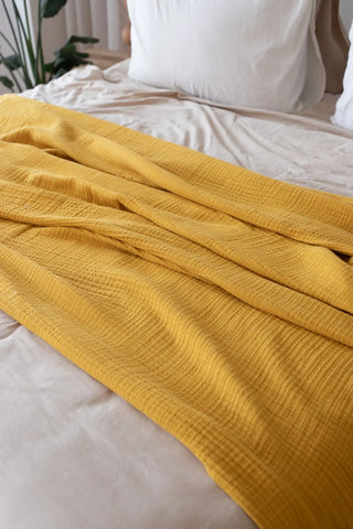 Mustard handwoven 4-layer muslin Turkish cotton bedspread folded flat lay. Long-staple Denizli, OEKO-TEX. Vivamaison.