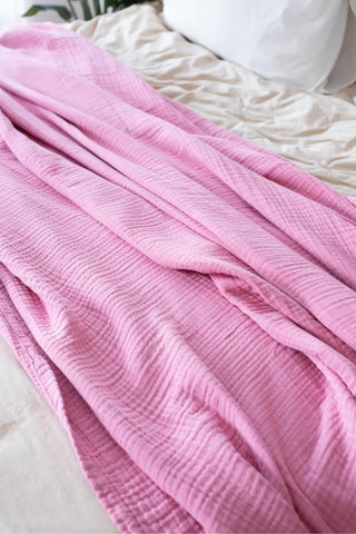 Pink handwoven 4-layer muslin Turkish cotton bedspread folded flat lay. Long-staple Denizli, OEKO-TEX. Vivamaison.
