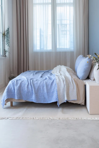 Baby Blue handwoven 4-layer soft muslin fringed bedspread folded flat lay. Tasseled edges, Denizli, OEKO-TEX. Vivamaison.