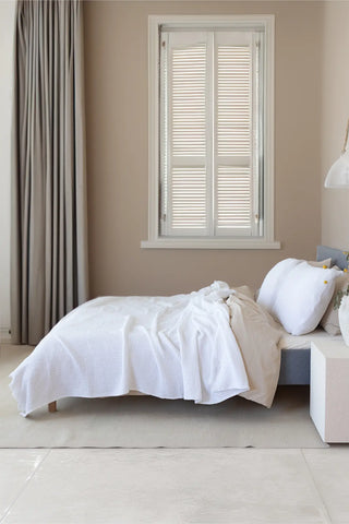 White handwoven 4-layer soft muslin fringed bedspread folded flat lay. Tasseled edges, Denizli, OEKO-TEX. Vivamaison.