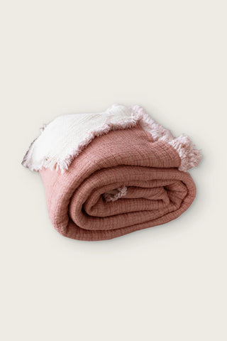 Handwoven 8-layer muslin Turkish cotton quilt in terracotta, rolled front view with hand-tied fringe