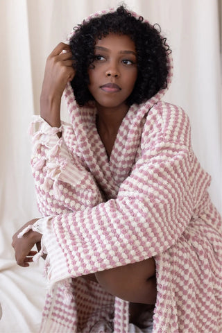 Light pink chickpea bathrobe hood up seated closeup. Handwoven Turkish cotton Denizli, OEKO-TEX. Vivamaison.