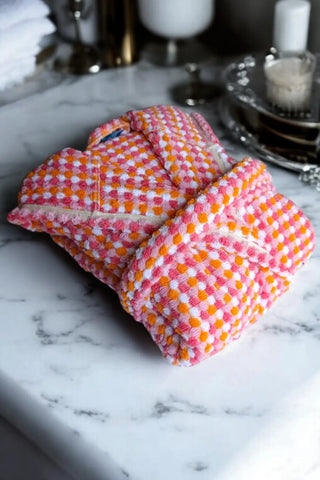 Pink orange chickpea bathrobe folded flat lay. Handwoven Turkish cotton Denizli, OEKO-TEX. Vivamaison.