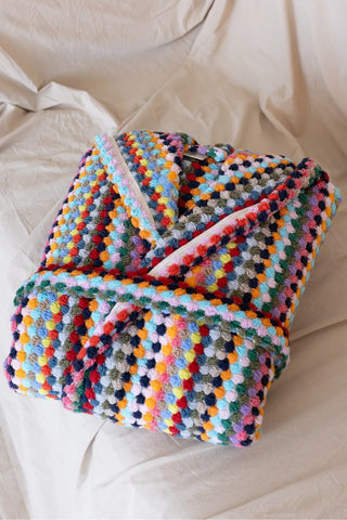 Rainbow chickpea bathrobe folded flat lay on bed. Handwoven Turkish cotton Denizli, OEKO-TEX. Vivamaison.
