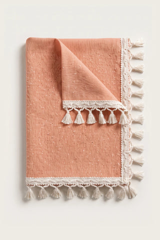 Handwoven Turkish cotton tassel tablecloth in orange, folded with corner turned back showing the tassel trim