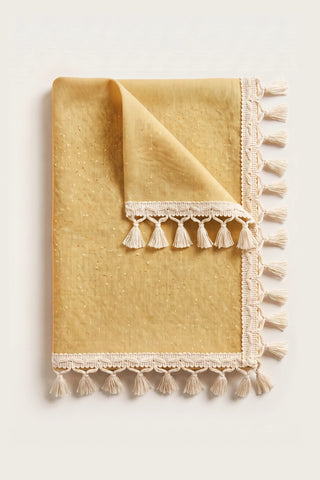 Handwoven Turkish cotton tassel tablecloth in yellow, folded with corner turned back showing the tassel trim