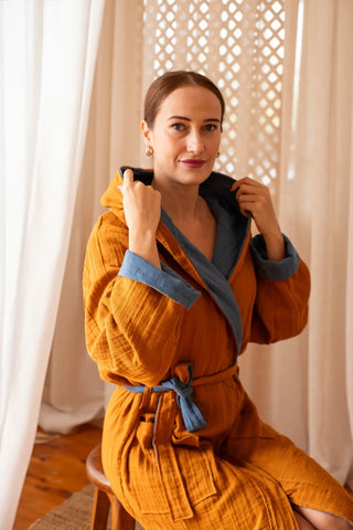 Reversible muslin bathrobe mustard outer indigo inner seated. Handwoven Turkish cotton Denizli, OEKO-TEX. Vivamaison.