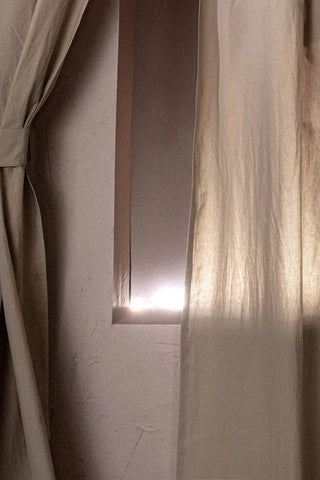 Backlit beige stonewashed cotton curtain panels by a narrow window. Handwoven in Denizli, OEKO-TEX. Vivamaison.