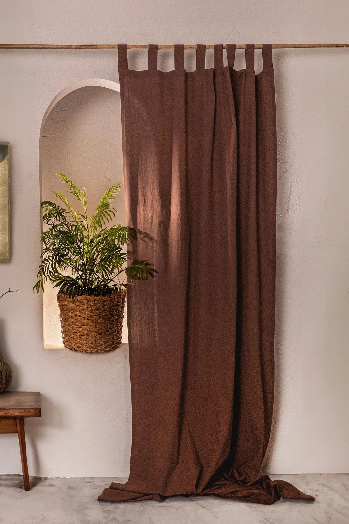 Brown stonewashed cotton curtain panel, tab top, beside a plant niche. Handwoven in Denizli, OEKO-TEX. Vivamaison.