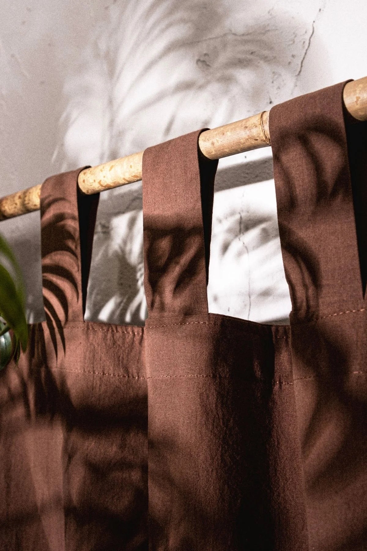 Brown stonewashed cotton curtain tab top loops on a bamboo rod, close-up. Handwoven in Denizli, OEKO-TEX. Vivamaison.