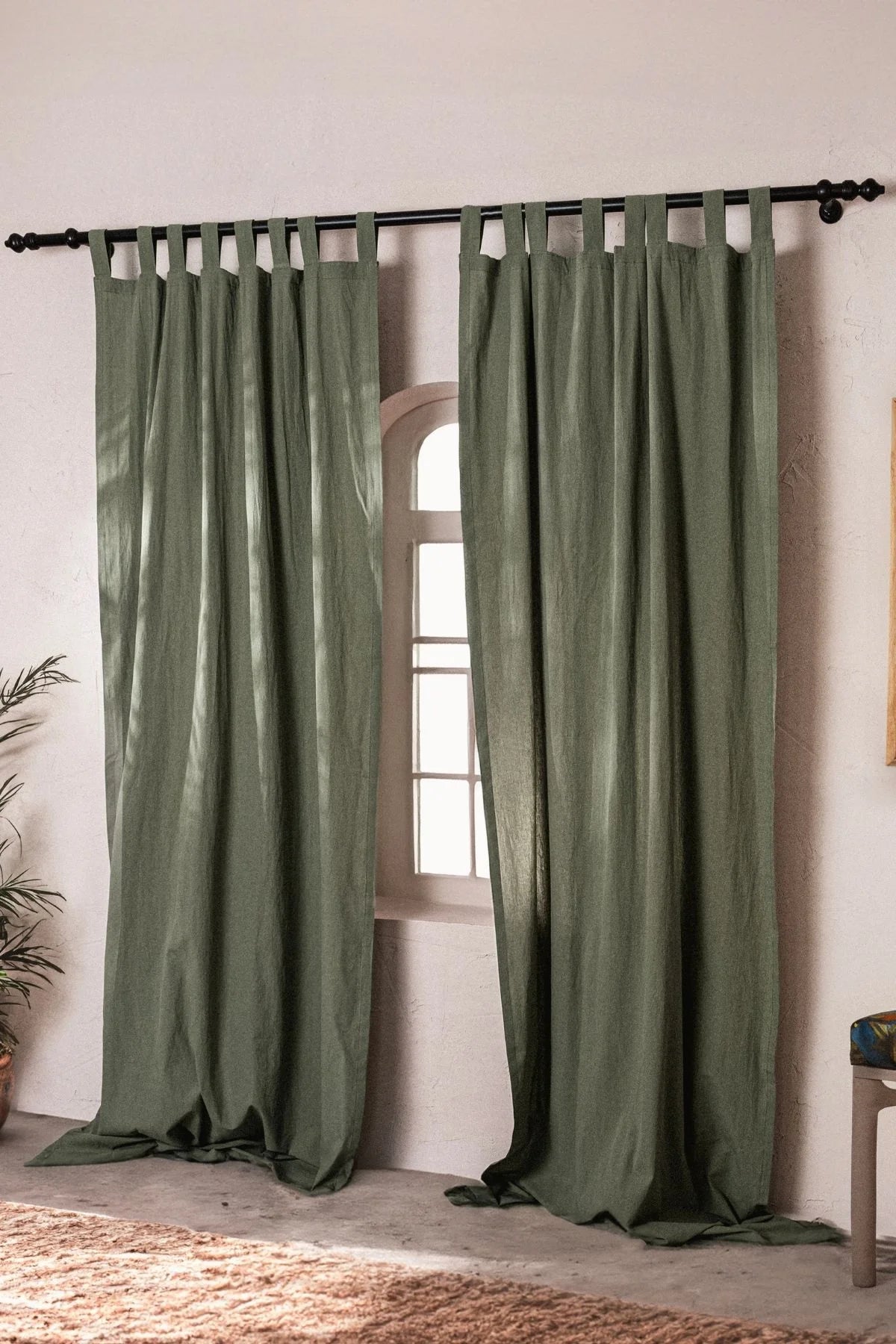 Dark green stonewashed cotton curtain panels framing an arched window. Handwoven in Denizli, OEKO-TEX. Vivamaison.