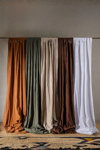 Five colors of the stonewashed cotton curtain panel hanging over a jute rug. Handwoven in Denizli, OEKO-TEX. Vivamaison.