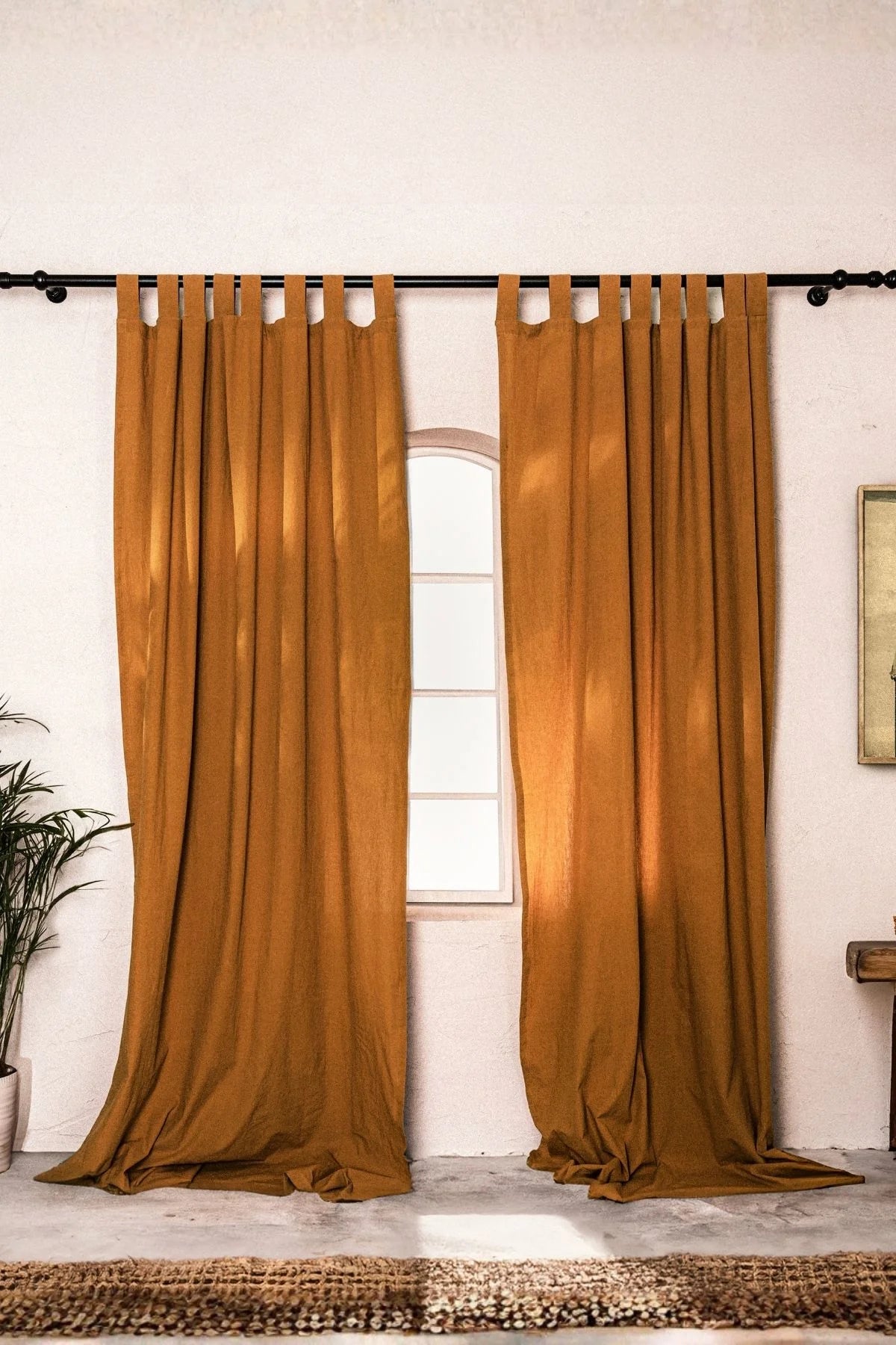 Terracotta stonewashed cotton curtain panels framing an arched window. Handwoven in Denizli, OEKO-TEX. Vivamaison.