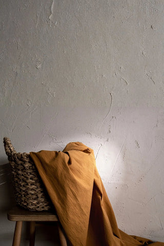 Terracotta stonewashed cotton curtain fabric draped over a basket. Handwoven in Denizli, OEKO-TEX. Vivamaison.