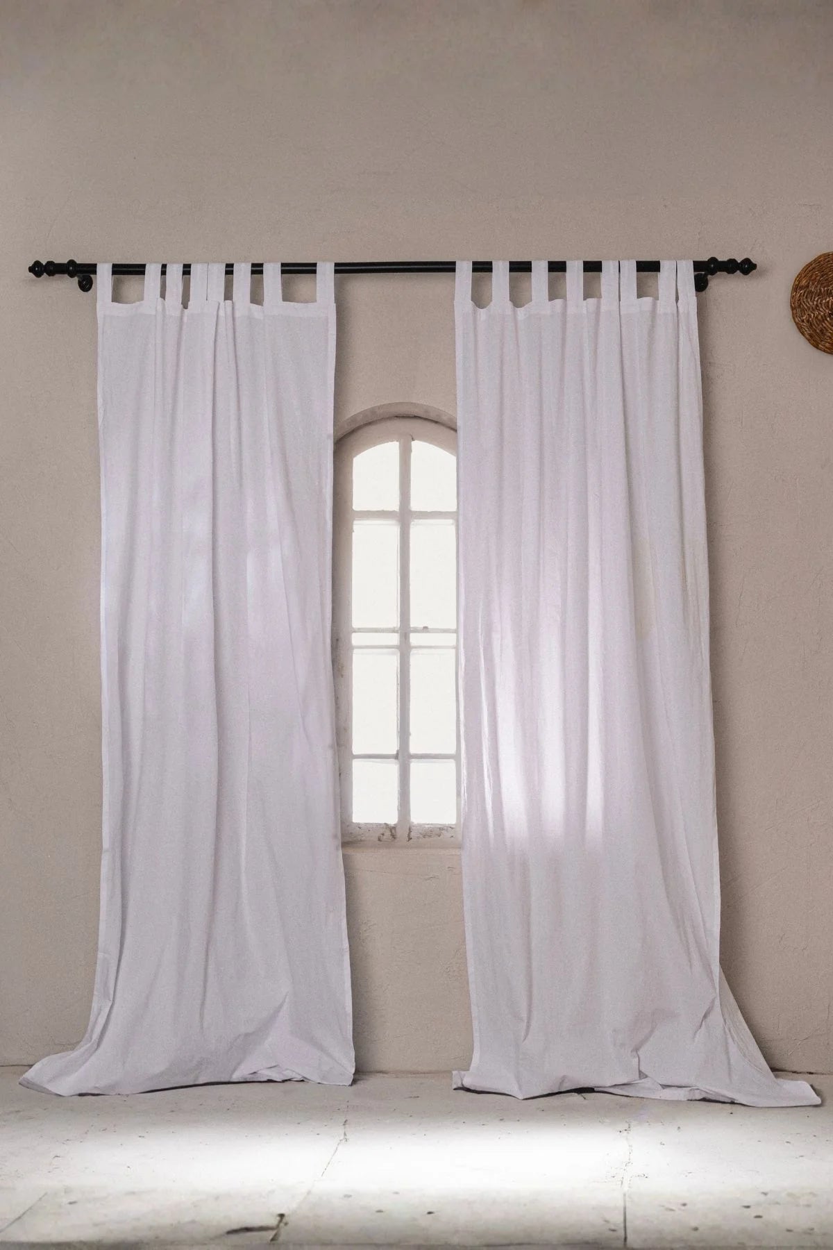 White stonewashed cotton curtain panels framing an arched window. Handwoven in Denizli, OEKO-TEX. Vivamaison.