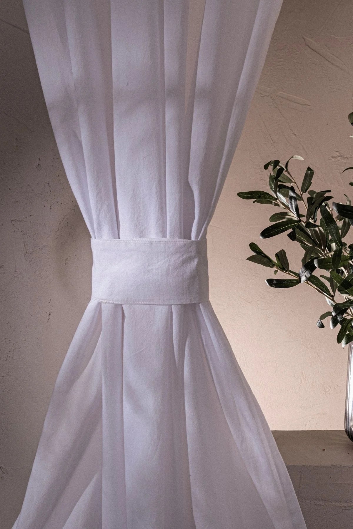 White stonewashed cotton curtain cinched with a tieback band, close-up. Handwoven in Denizli, OEKO-TEX. Vivamaison.