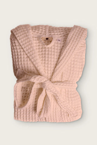 Handwoven waffle hooded bathrobe in pink, folded front view with tied belt