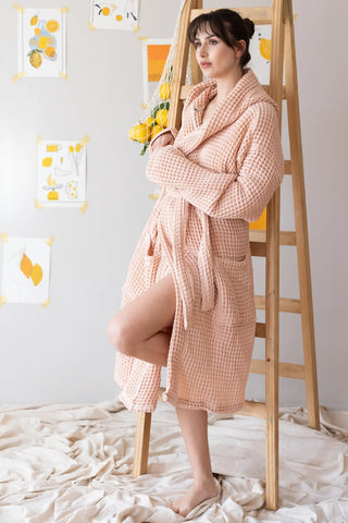 Handwoven waffle hooded bathrobe in pink, side full view on ladder. Turkish cotton Denizli, OEKO-TEX. Vivamaison.