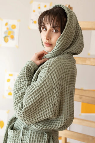 Close-up waffle weave texture on sage green hooded bathrobe. Handwoven Turkish cotton, Denizli heritage. Vivamaison.