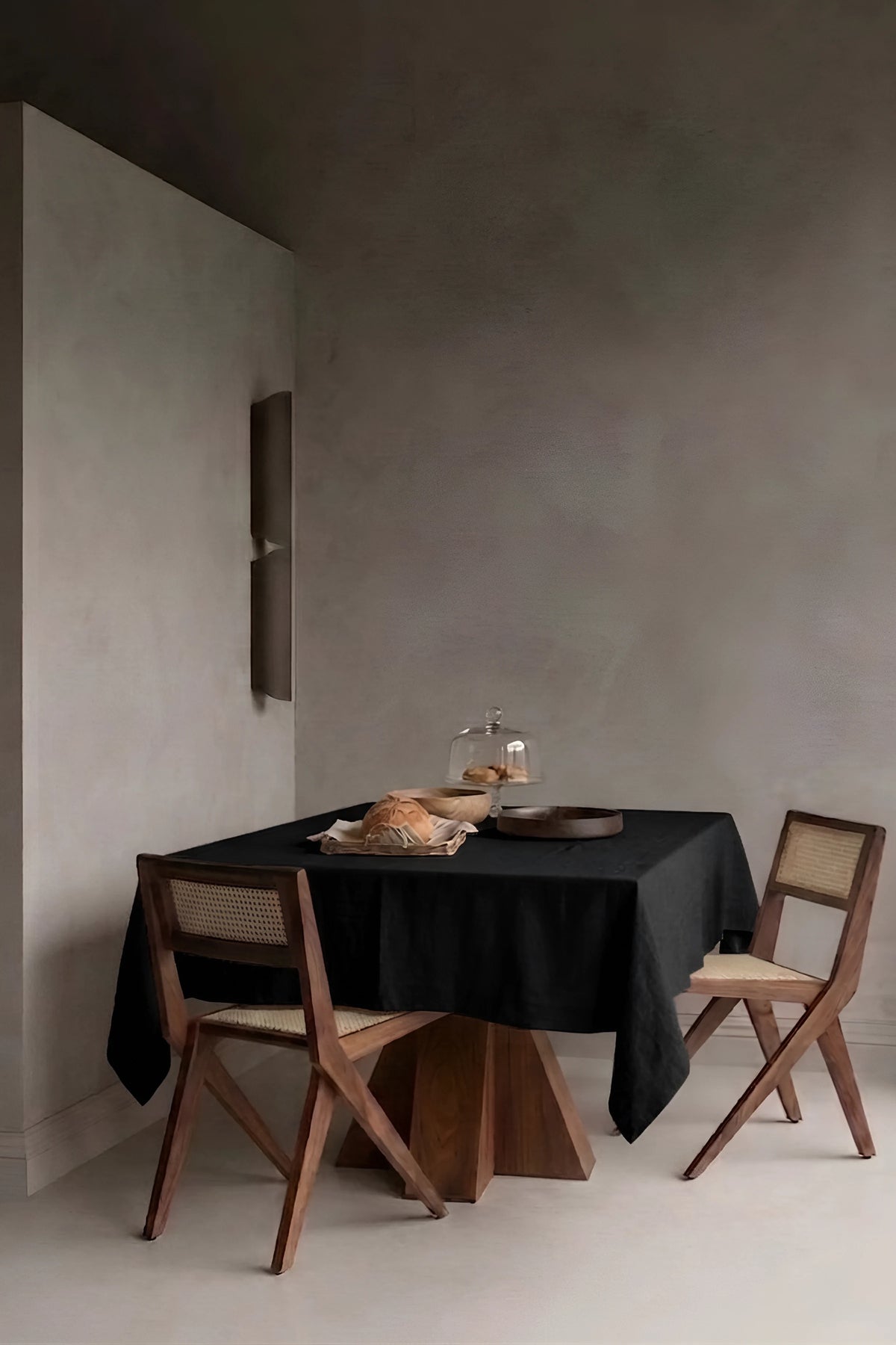 Black plain linen cotton blend tablecloth on a dining table in a modern dining room with cane chairs. 9 sizes, handmade in Denizli, OEKO-TEX. VivaMaison.