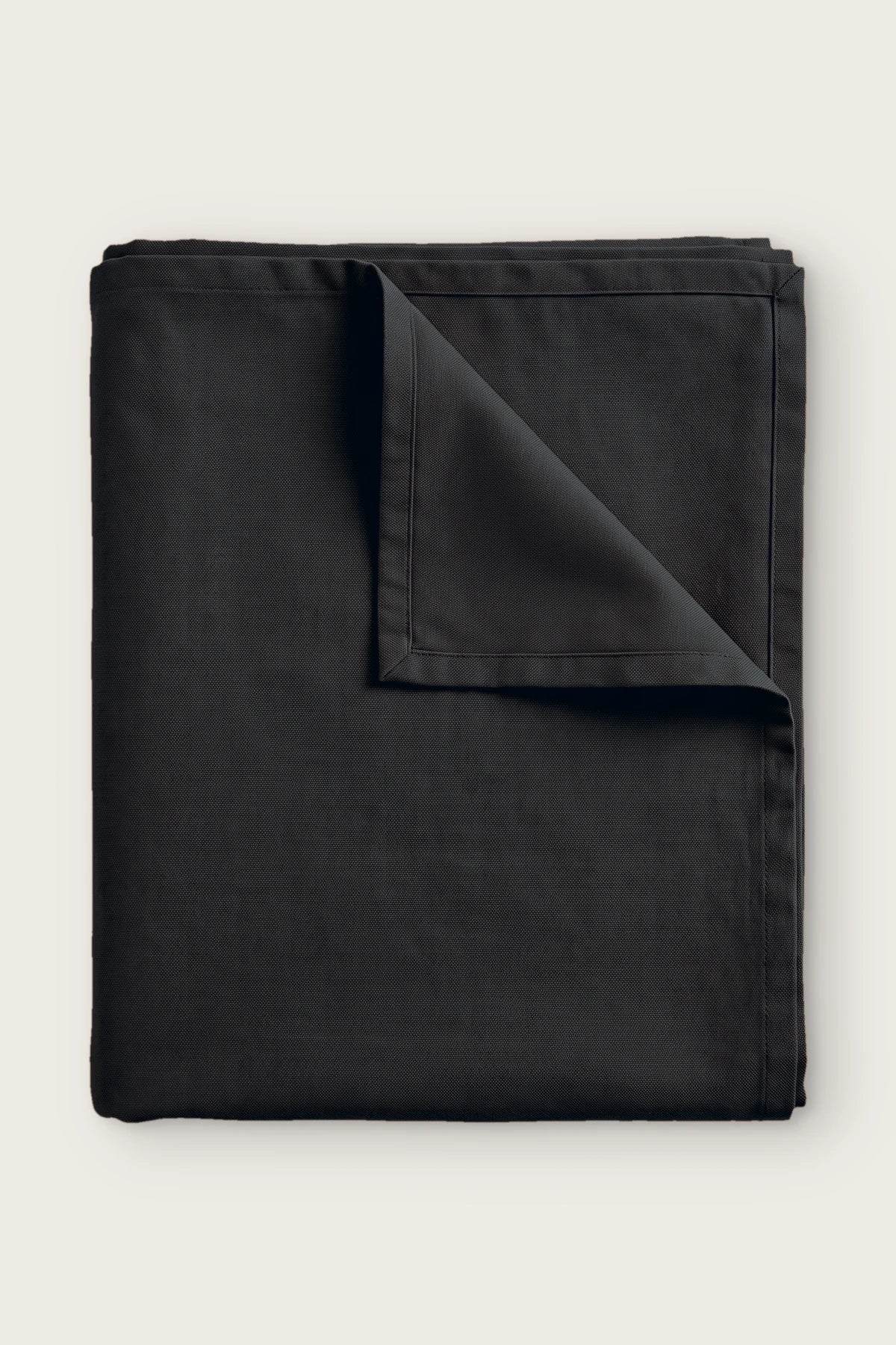 Plain linen cotton blend tablecloth in black, folded with corner turned back