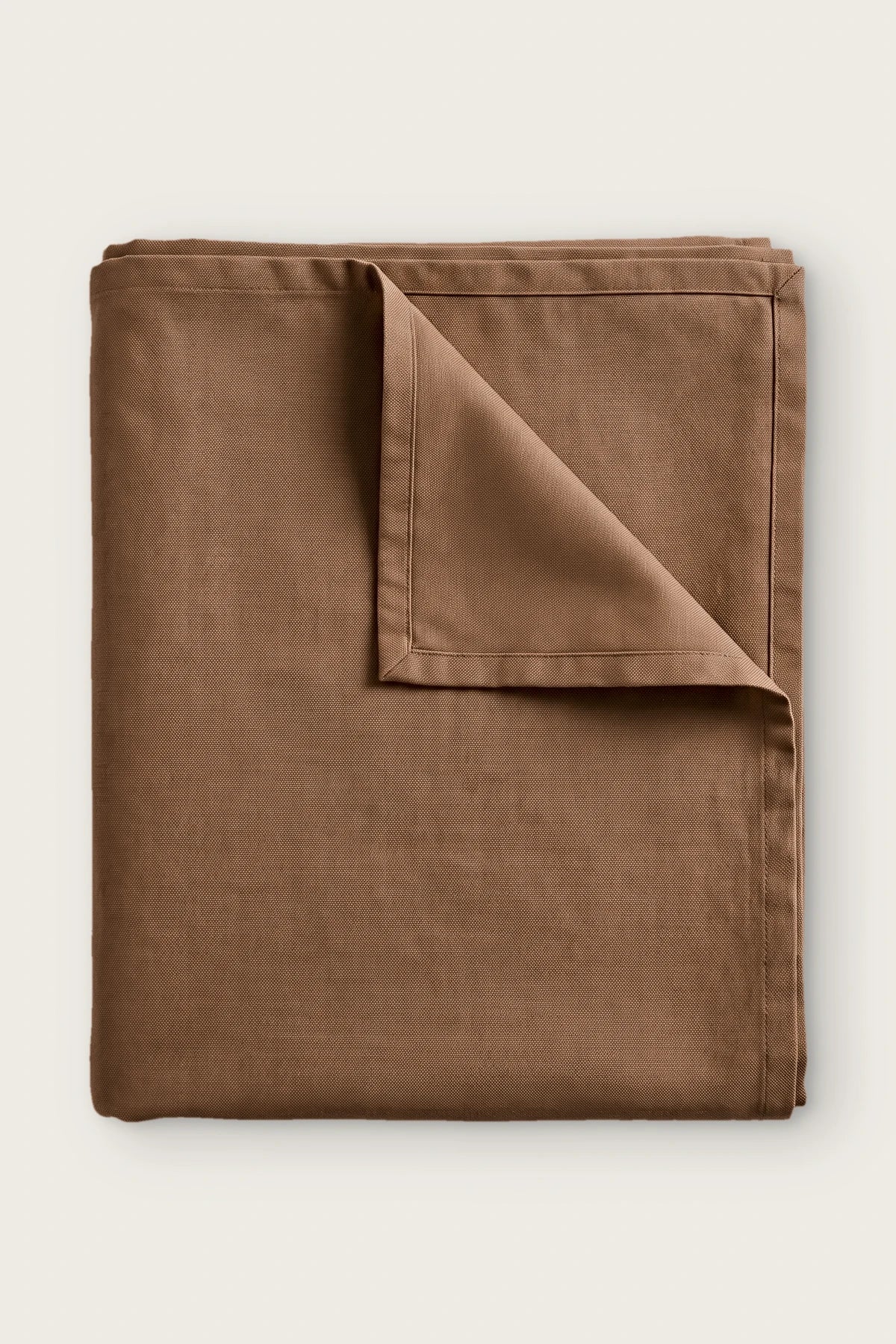 Plain linen cotton blend tablecloth in brown, folded with corner turned back