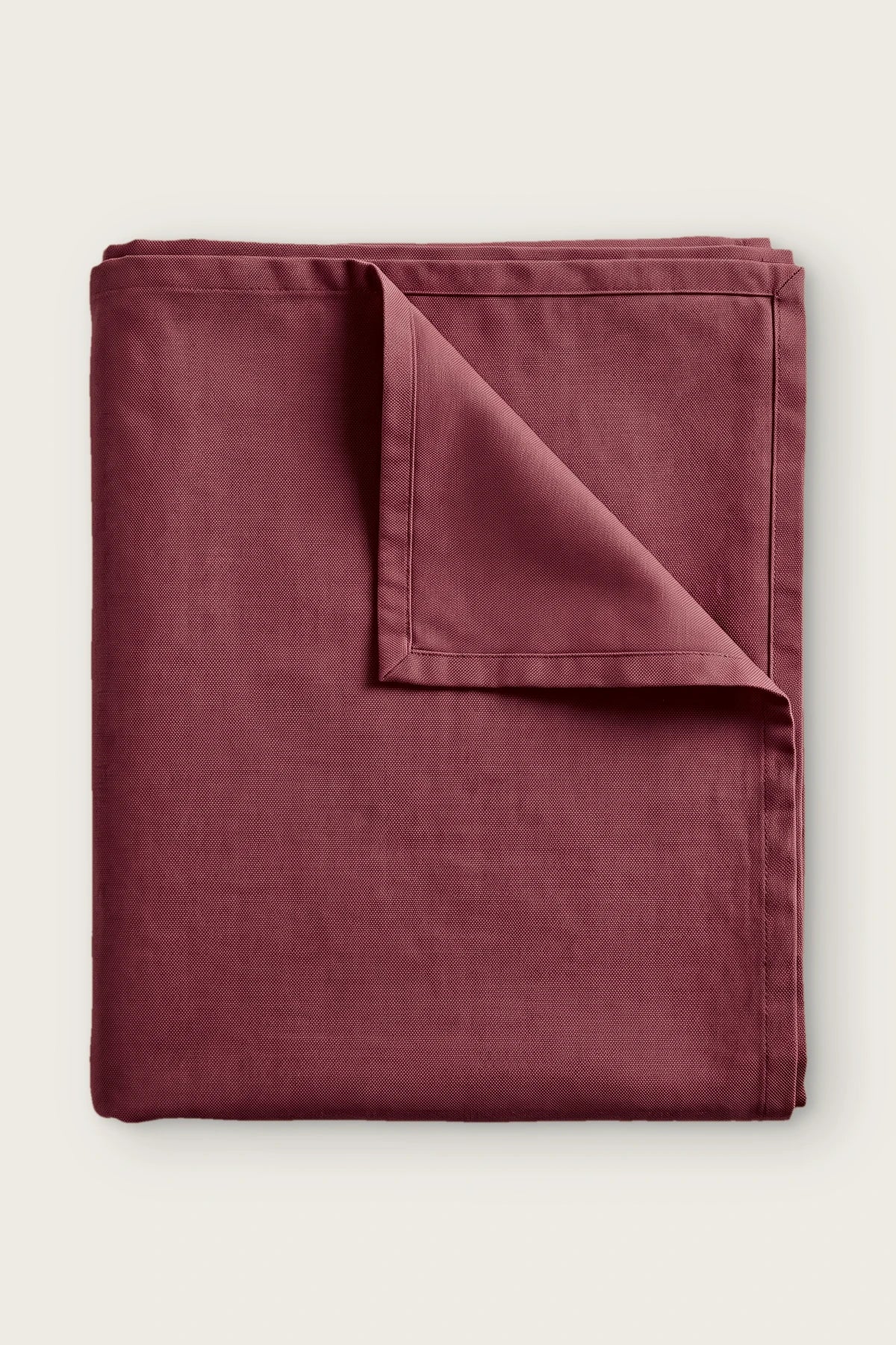 Plain linen cotton blend tablecloth in burgundy, folded with corner turned back