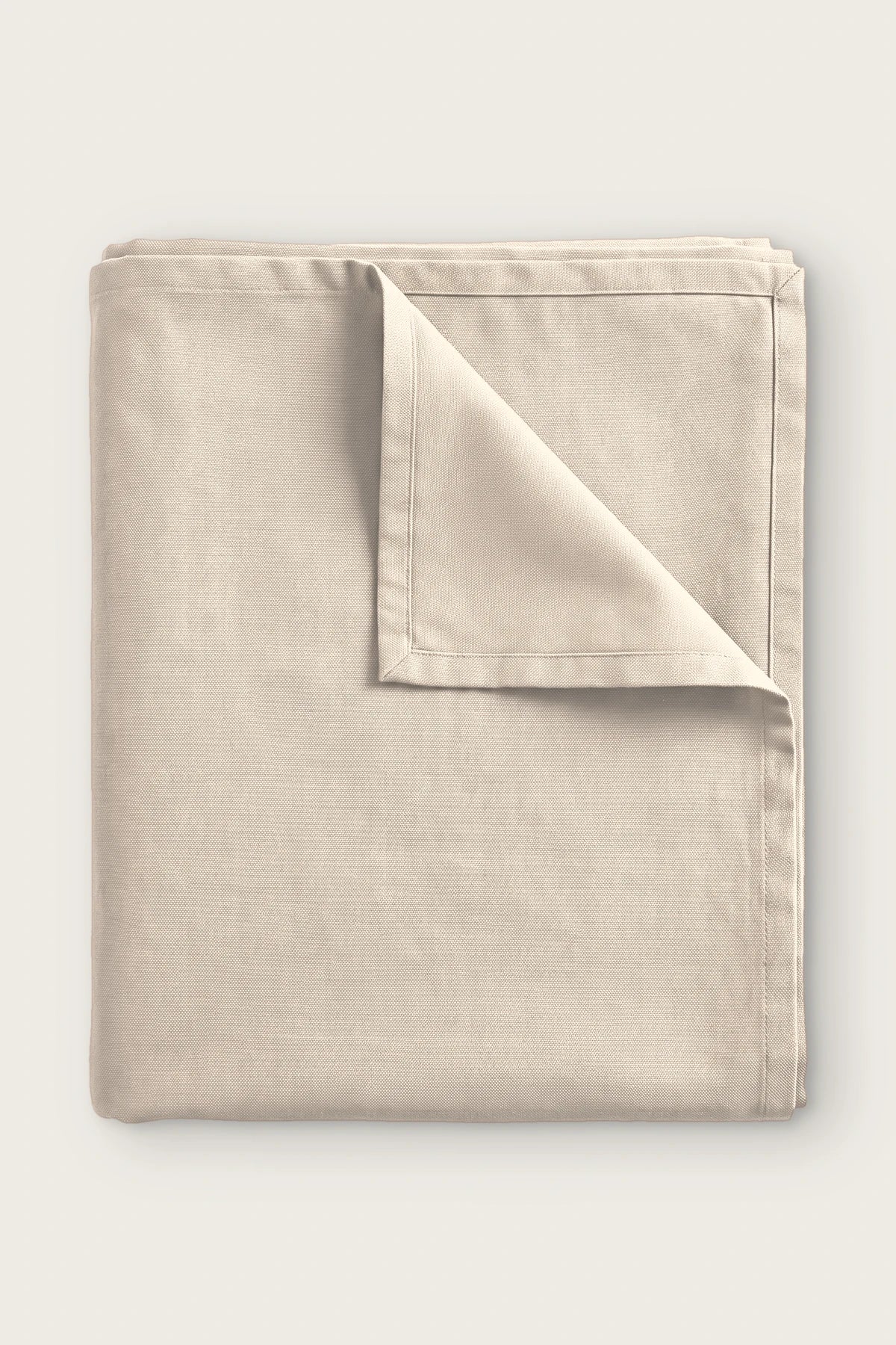 Plain linen cotton blend tablecloth in natural, folded with corner turned back