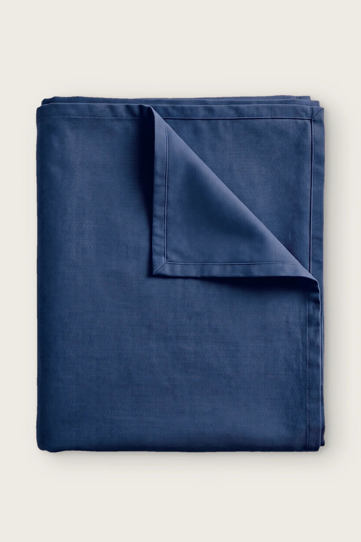 Plain linen cotton blend tablecloth in navy, folded with corner turned back