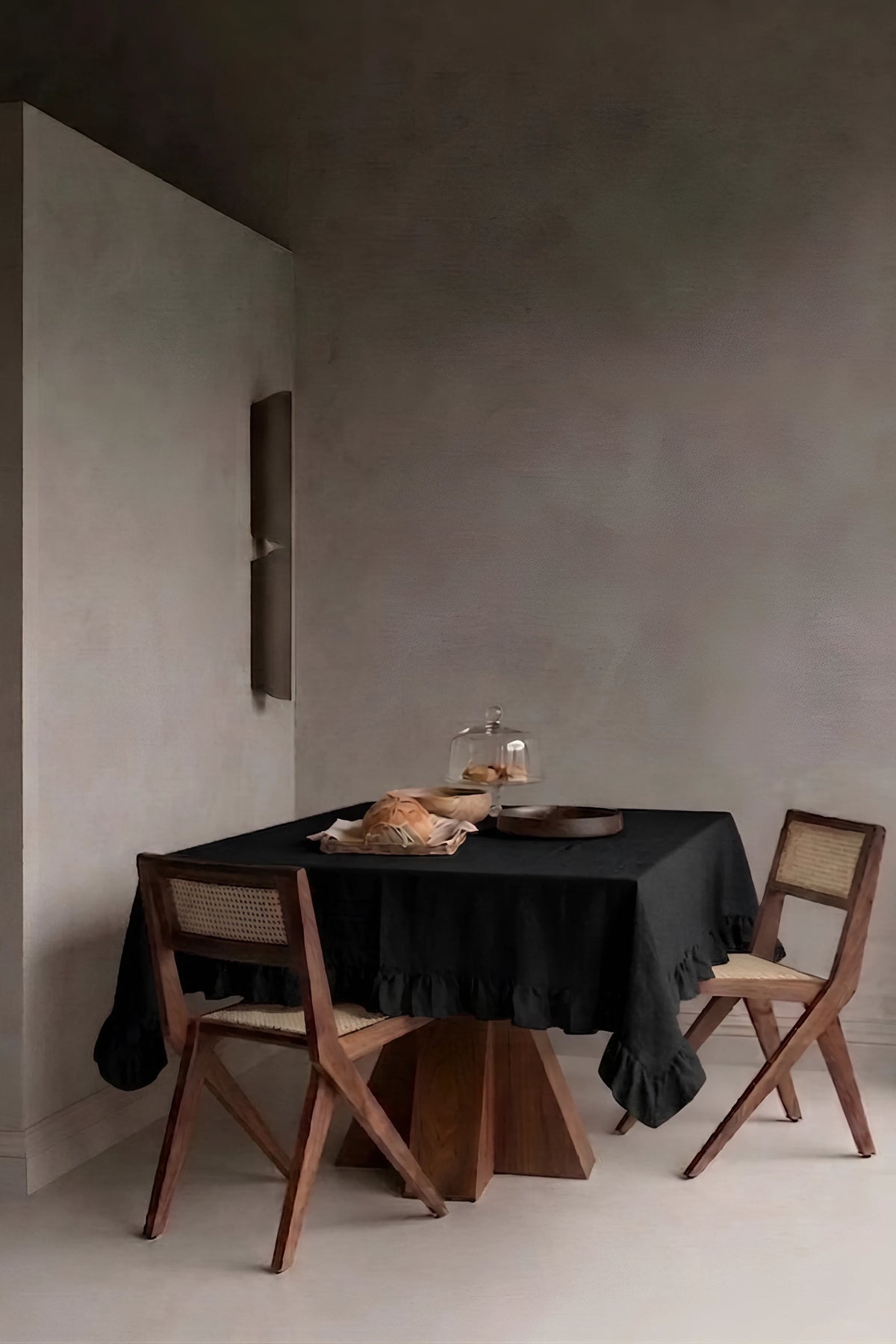 Black ruffled linen cotton blend tablecloth on a dining table in a modern dining room with cane chairs. 9 sizes, handmade in Denizli, OEKO-TEX. VivaMaison.