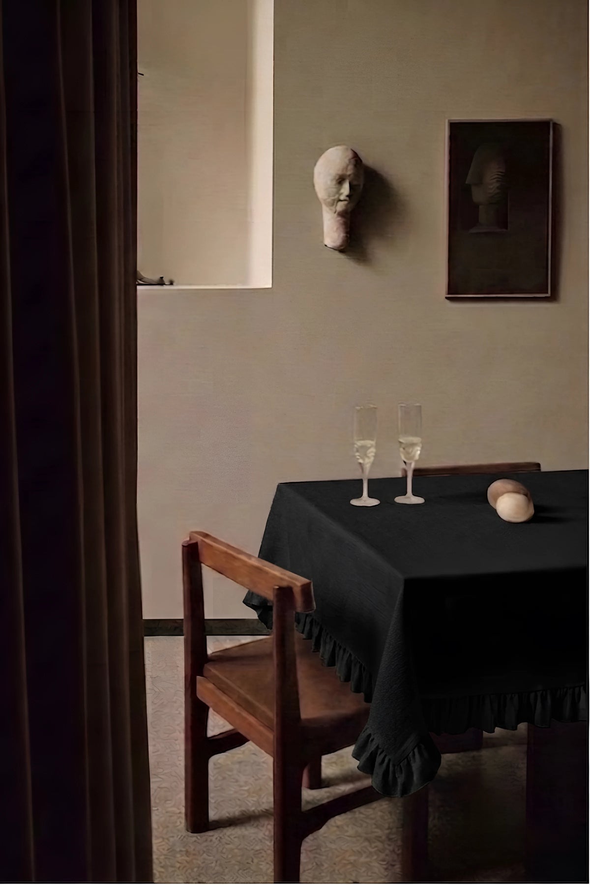 Black ruffled linen cotton blend tablecloth on a dining table with champagne flutes, seen through a doorway. 9 sizes, handmade in Denizli, OEKO-TEX. VivaMaison.