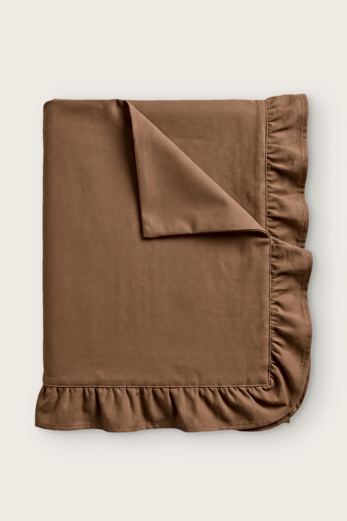 Ruffled linen cotton blend tablecloth in brown, folded with corner turned back
