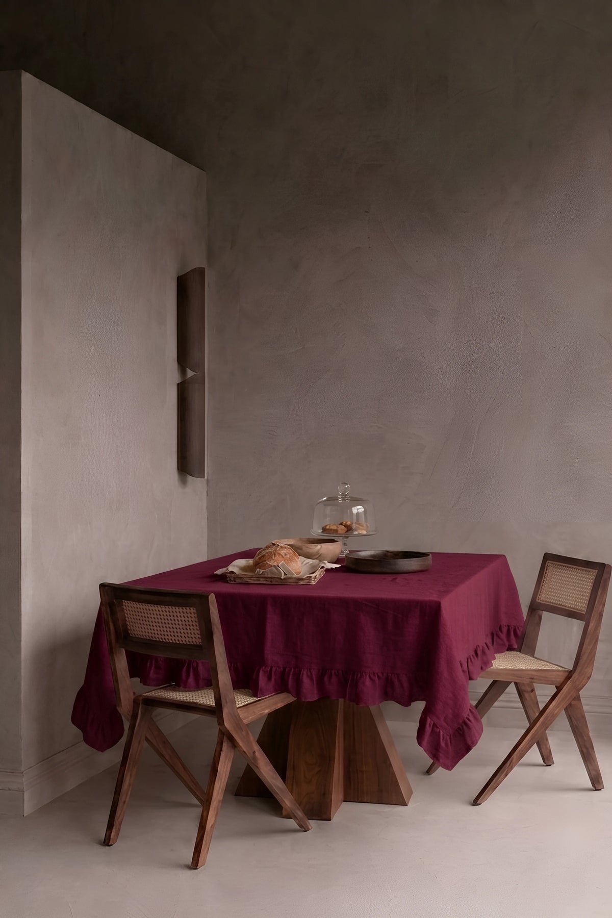 Burgundy ruffled linen cotton blend tablecloth on a dining table in a modern dining room with cane chairs. 9 sizes, handmade in Denizli, OEKO-TEX. VivaMaison.