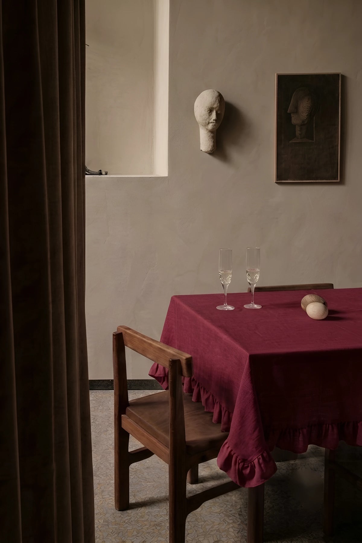Burgundy ruffled linen cotton blend tablecloth on a dining table with champagne flutes, seen through a doorway. 9 sizes, handmade in Denizli, OEKO-TEX. VivaMaison.