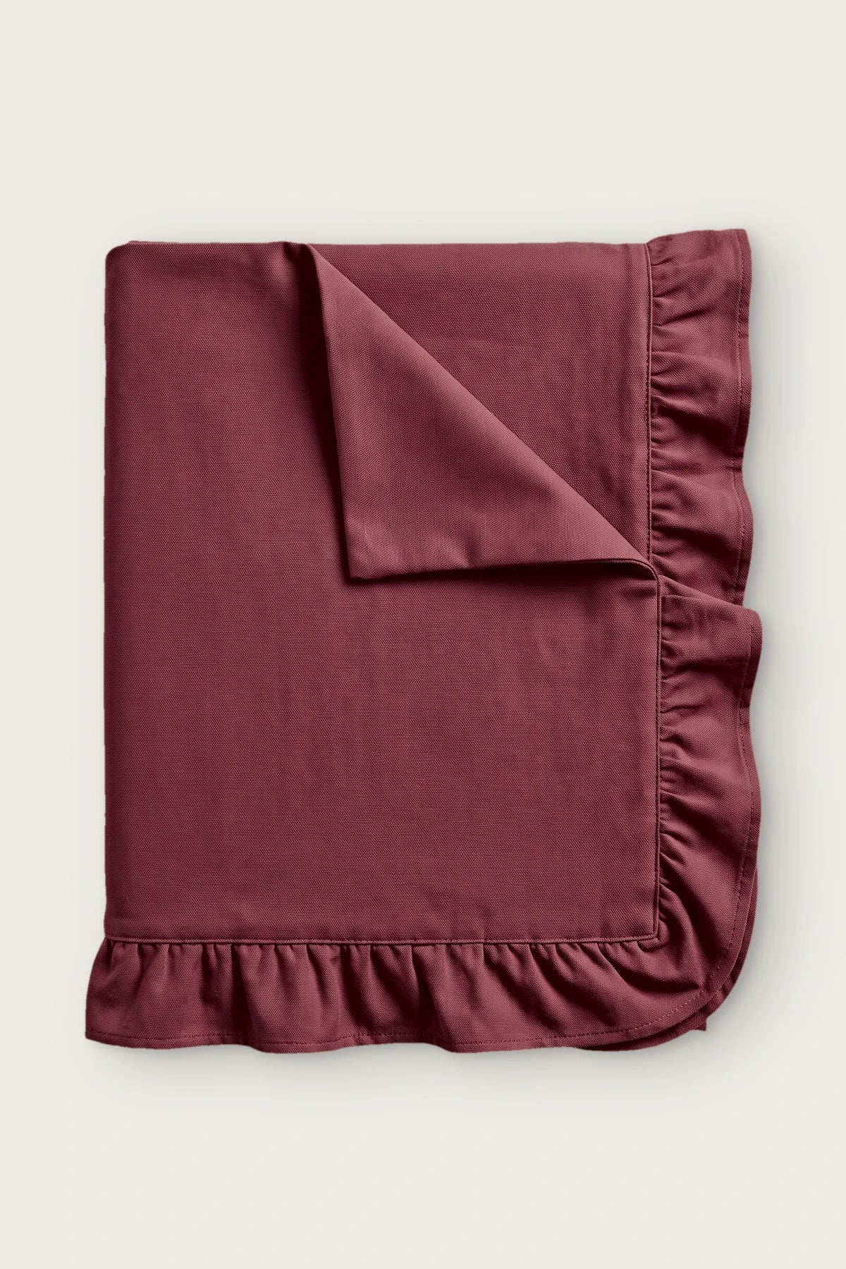 Ruffled linen cotton blend tablecloth in burgundy, folded with corner turned back