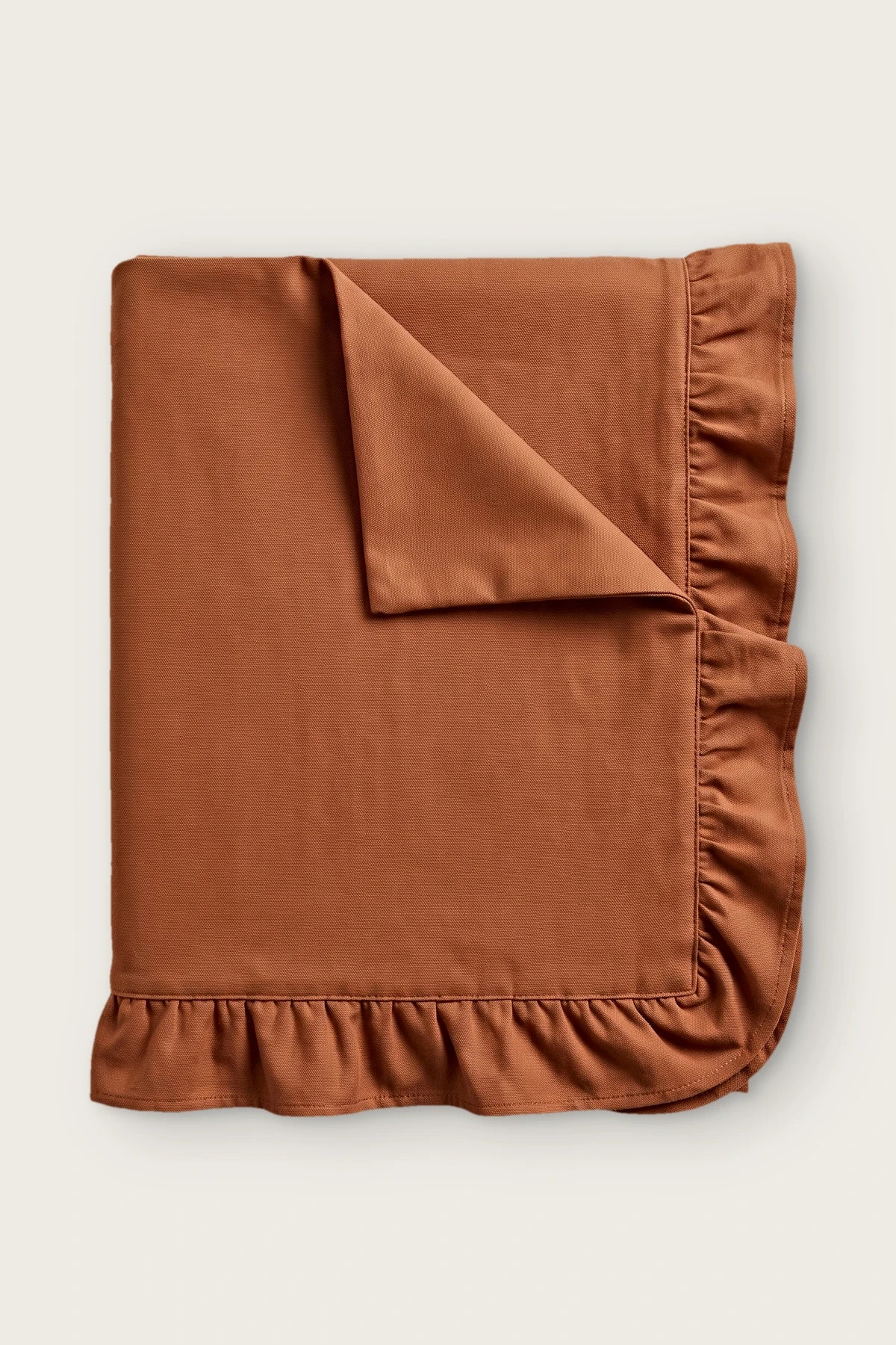 Ruffled linen cotton blend tablecloth in cinnamon, folded with corner turned back
