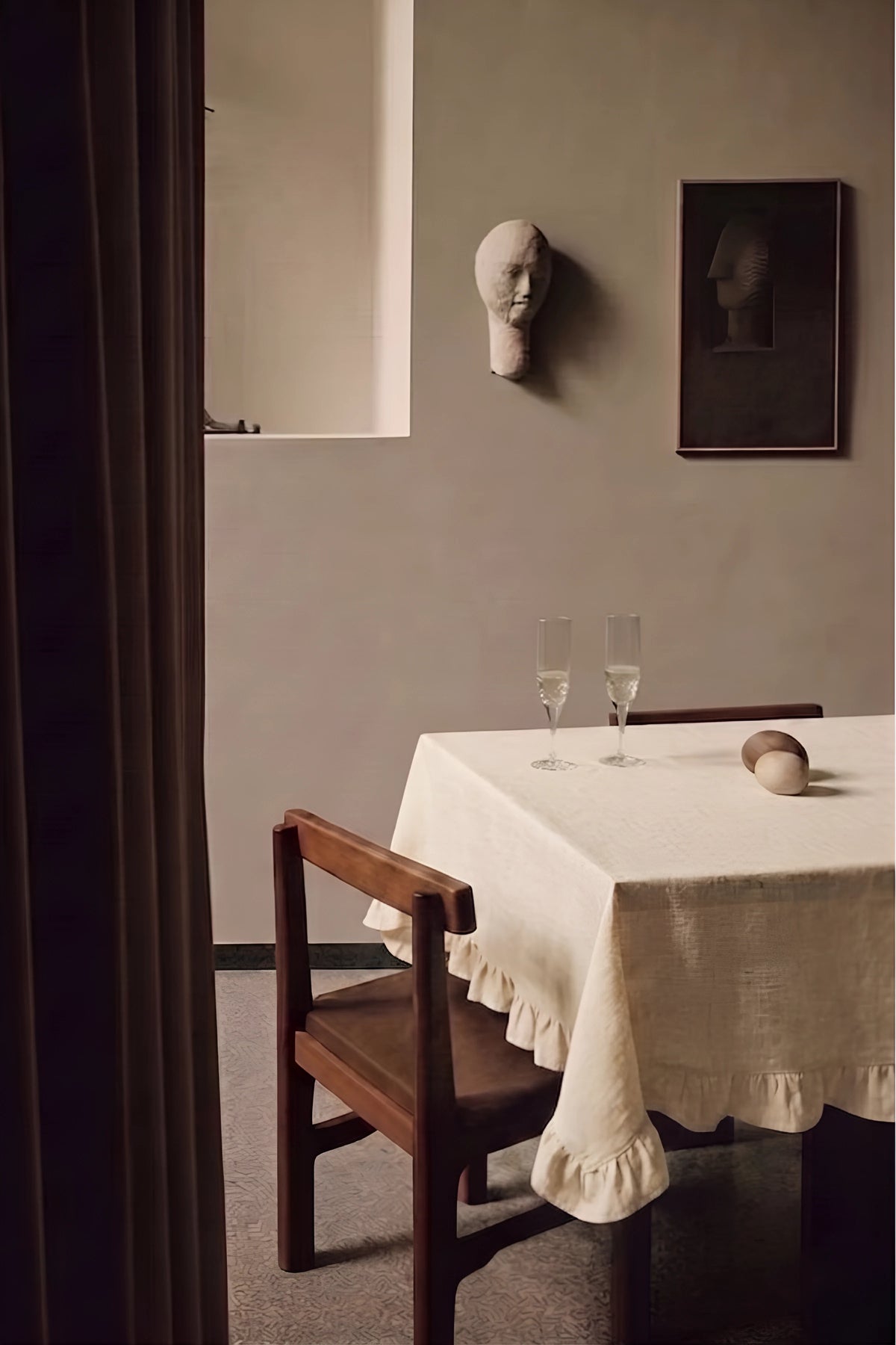 Natural ruffled linen cotton blend tablecloth on a dining table with champagne flutes, seen through a doorway. 9 sizes, handmade in Denizli, OEKO-TEX. VivaMaison.