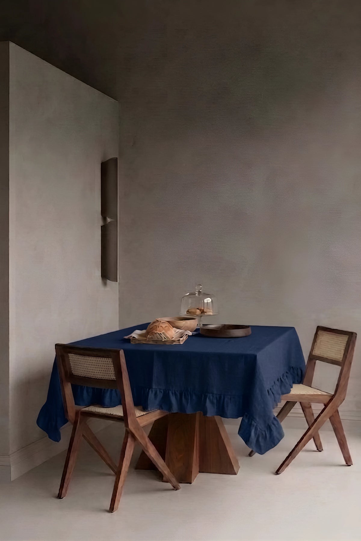 Navy ruffled linen cotton blend tablecloth on a dining table in a modern dining room with cane chairs. 9 sizes, handmade in Denizli, OEKO-TEX. VivaMaison.
