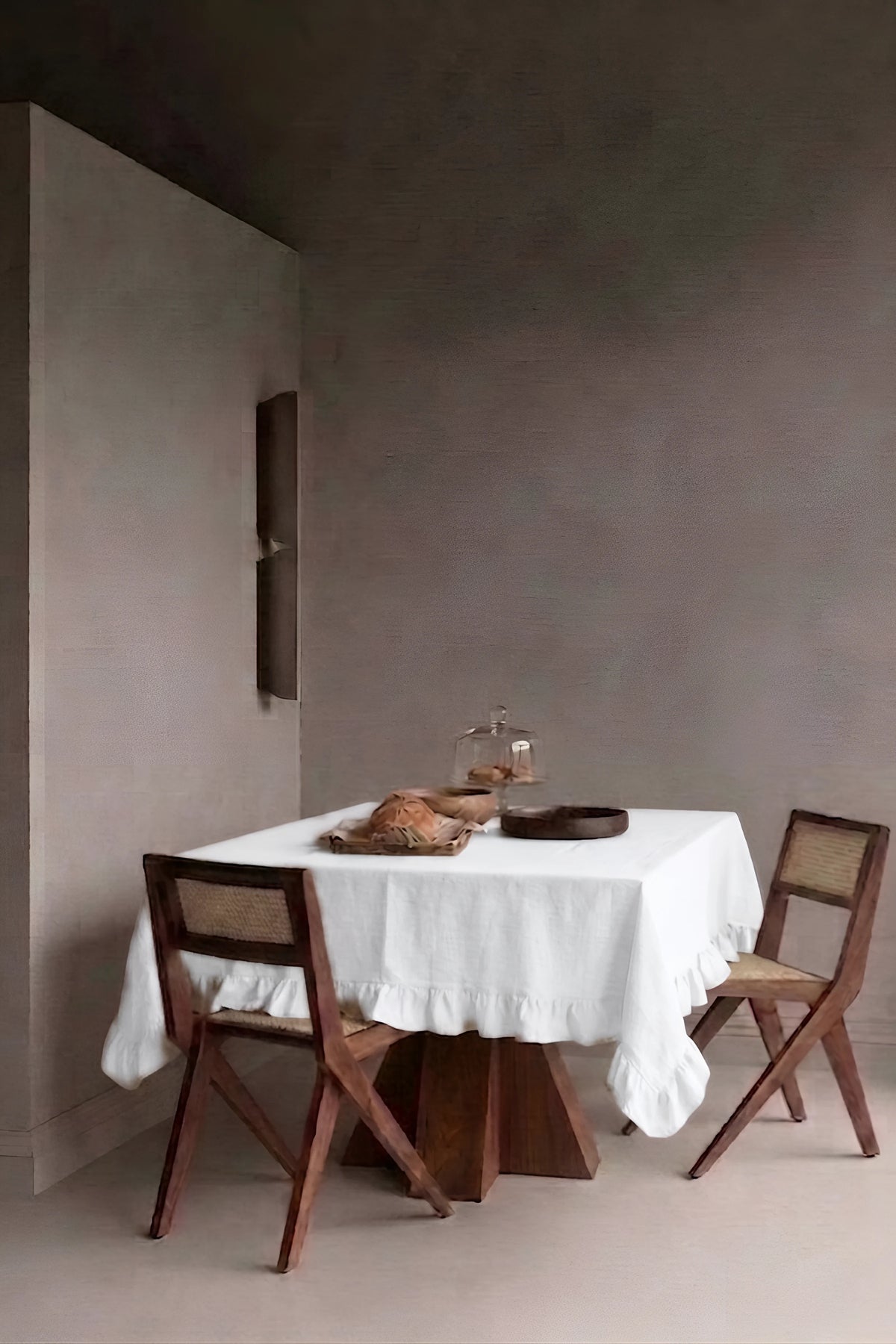 White ruffled linen cotton blend tablecloth on a dining table in a modern dining room with cane chairs. 9 sizes, handmade in Denizli, OEKO-TEX. VivaMaison.