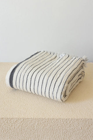 Muslin striped Turkish cotton beach towel peshtemal with black stripes folded on stone pedestal - VivaMaison