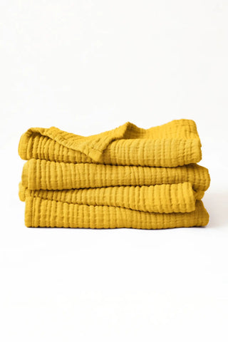 Stacked mustard muslin Turkish cotton towels with soft 4-layer gauze weave, handwoven in Denizli