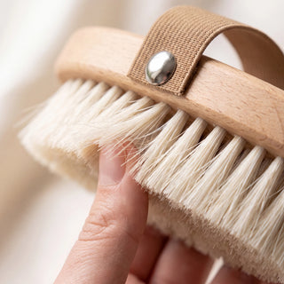 Fingertips pressing into the soft natural bristles of the dry body brush - VivaMaison