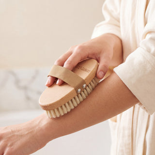 Natural bristle dry body brush held in the hand with the strap over the back of the hand - VivaMaison